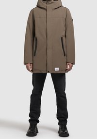 Parka marrón con aislamiento y capucha, que presenta dos bolsillos laterales con cremallera, un corte recto y detalles en negro en los bolsillos y botones.