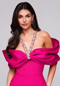 Fuksiaväri strapless-mekko, jossa on ylisuuria nauhahartioita kauluksessa, jotka on koristeltu kukkakristalleilla. Sileä pinta.