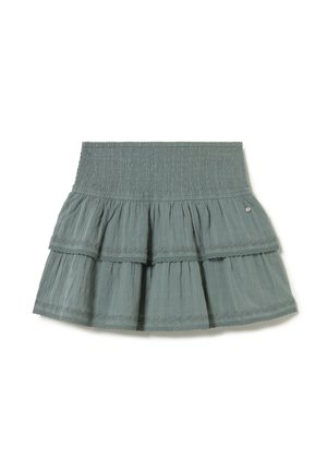 Mini-jupe verte à volants avec ceinture smockée et détail subtil de bordure en dentelle sur chaque couche.