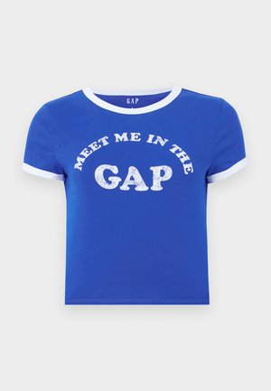 T-shirt en coton bleu avec un col rond et des poignets de manches blancs. Présente un texte à l'avant disant "RENCONTRE MOI DANS LE DÉCALAGE" en impression blanche vieillie.