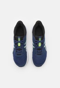 Baskets de sport navy avec une tige en mesh, intérieur noir, semelle blanche et logo visible. Présente des accents de lacets verts et des détails cousus.
