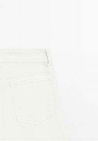 Jean en denim blanc montrant la poche arrière et la boucle de ceinture sur un fond blanc uni.