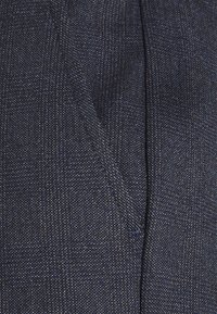 Mörkblå, texturerad tyg med ett subtilt mönster. Har en sydd söm och en detalj med framficka. Materialet verkar lätt och vävt.