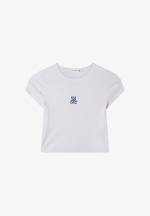 T-shirt di cotone bianco con maniche corte, con un orsetto ricamato blu sul davanti. Design semplice con colletto girocollo e vestibilità rilassata.