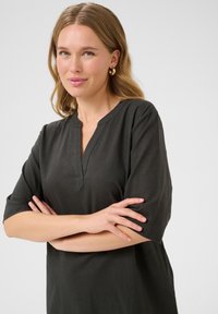Haut en lin gris foncé à manches courtes avec un design en V et une coupe décontractée, présentant des détails de couture subtils le long de l'encolure.