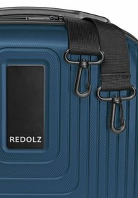 Donkerblauwe, textuurachtige koffer met zwarte draaiclips bevestigd aan een afneembare zwarte schouderband, met een zwart label met witte "REDOLZ" tekst.