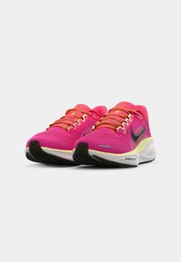 Pink athletic shoes featuring a mesh upper, contrasting orange laces, black accents, and a cushioned white sole with a textured grip pattern.