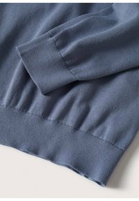 Pull en tricot bleu avec poignets et ourlet côtelés, une texture lisse et une coupe décontractée, conçu pour le confort et la facilité de port.