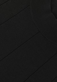 Melna adīta džemperis ar ribotu tekstūru, ar apaļu kakla izgriezumu un smalku vertikālu svītru apdari visā audumā.