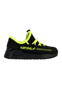 Zapatilla negra con un upper texturizado, acentos en amarillo neón y una suela negra resistente. Nombre de la marca "KAPORAL" visible en el lateral.