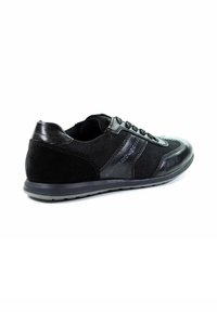 Schwarzer Sneaker aus einer Kombination von glattem Leder und strukturiertem Stoff. Merkmale sind ein niedriges Profil, ein schnürbares Design und eine Gummisohle.