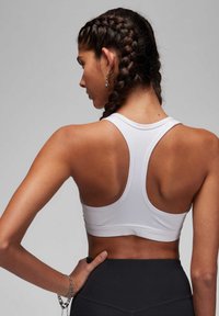 Witte sportbeha met een scoop rug en brede banden, gemaakt van gladde, rekbare stof. Het ontwerp heeft een subtiele band aan de onderrand.