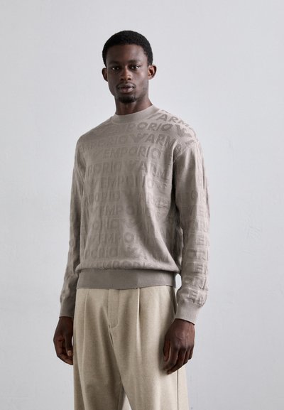 Maglione lavorato a maglia di colore beige chiaro con un motivo testurizzato della parola "Emporio" in diverse dimensioni. Collo e orlo a coste, vestibilità comoda.