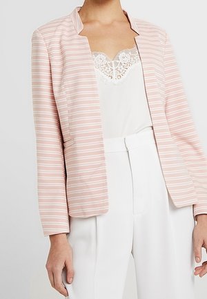 Blazer rayé rose au design sans col, fabriqué en tissu lisse. Il comporte deux poches avant, associé à un débardeur en dentelle blanche.