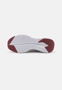 Shoe sole with a textured white rubber base and red accents. Features deep grooves for traction and stability.