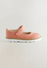 Różowe skórzane buty Mary Jane z rzepem, perforowanymi akcentami w kształcie serca, okrągłym czubkiem i białą, teksturowaną gumową podeszwą.