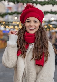 Berlina rossa con pompon, sciarpa rossa abbinata e un cappotto bianco peloso; texture calde, colori vivaci e elementi di design casual.
