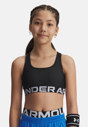 Czarny stanik sportowy z grubym, elastycznym pasem z logo Under Armour. Uzupełniony niebieskimi szortami sportowymi i czarną opaską na nadgarstek. Gładka tekstura materiału.