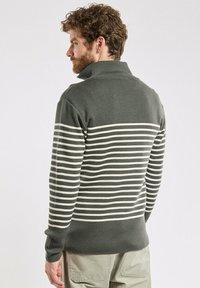 Zielony i kremowy sweter w paski z kołnierzykiem, który można złożyć. Wykonany z miękkiej dzianiny, ma długie rękawy i dopasowany krój u dołu.