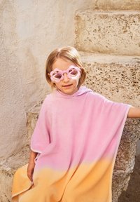 Ροζ και κίτρινη ομπρέ πόντσο με καπό, φτιαγμένο από μαλακό ύφασμα. Το παιδί φορά ροζ λουλουδάτα γυαλιά ηλίου, καθισμένο σε πέτρινες σκάλες.