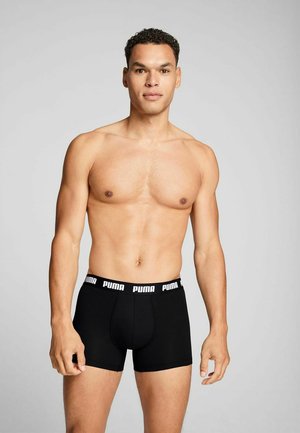 Black boxer shorts with a white Puma logo waistband, made from a soft, stretchy fabric, featuring a fitted design and smooth texture.