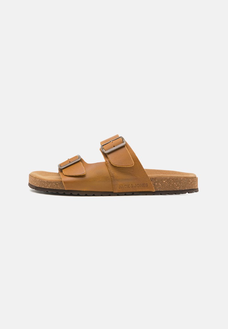 Brown leather sandals with two adjustable buckles, a cork footbed, and a textured rubber sole, featuring the brand name embossed on the side.