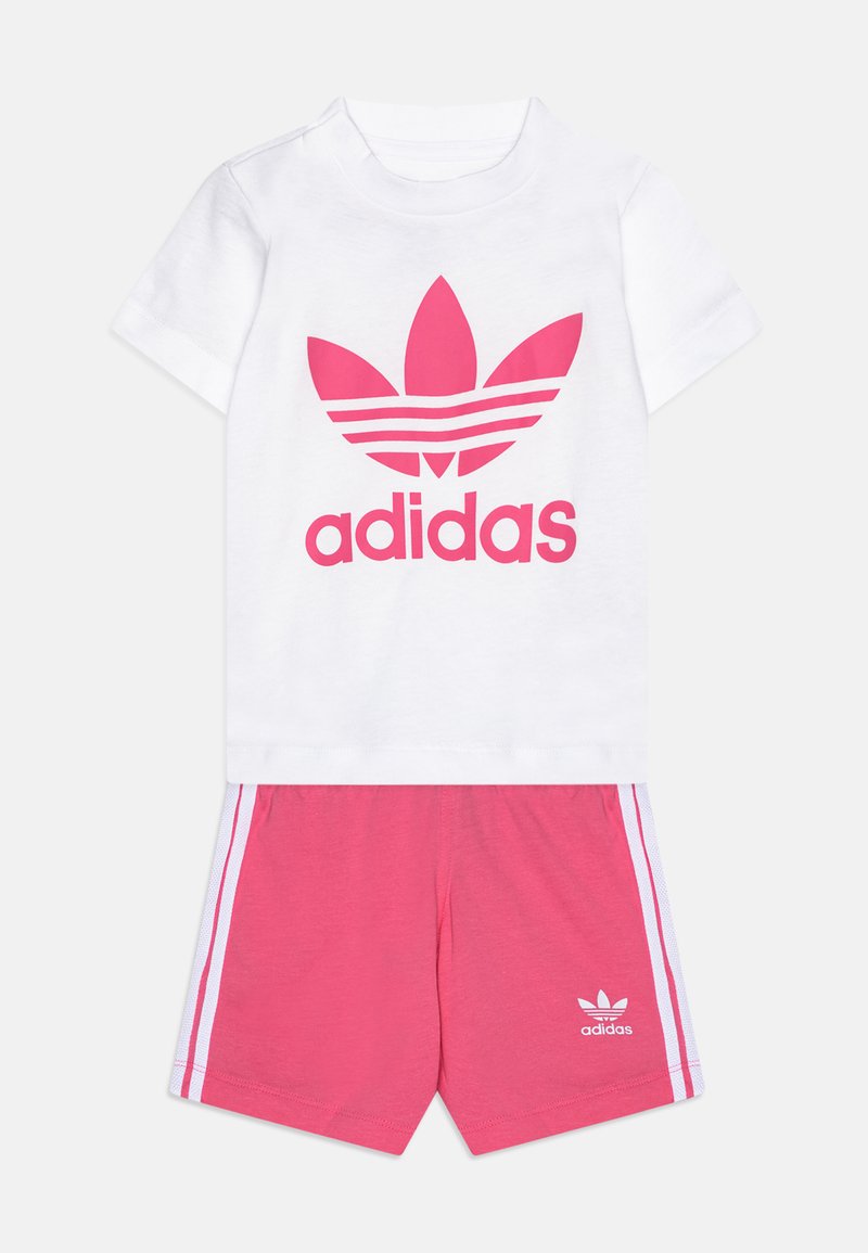 White cotton t-shirt with large pink Adidas logo; pink shorts with white side stripes and logo on the hem.