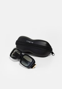 Black sunglasses with square frames and gradient lenses, accompanied by a black hard case featuring a zip closure and "vogue" branding.