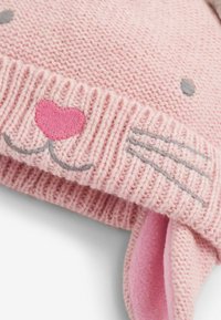 Gorro de punto rosa con diseño de conejo, detalles faciales bordados, suaves acentos en las orejas de color rosa y ribete acanalado para añadir textura.