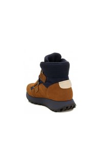 Braune Wildleder- und marineblaue Stoffstiefel mit einem strukturierten Schaftrand, verstellbaren Riemen und einer schwarzen Gummisohle, die an der Ferse einen weißen Akzent aufweist.