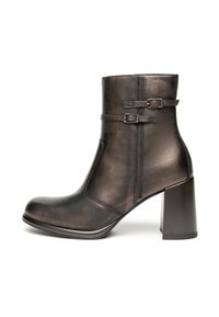 Bottines noires en cuiravec un bout arrondi, tige mi-haute, deux accents de boucle et un talon bloc épais. Texture lisse avec un subtil éclat.