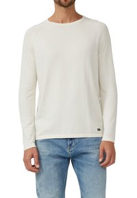 Weißes Langarmshirt mit rundem Ausschnitt, gefertigt aus weichem Stoff. Dezente Nähte und ein kleines schwarzes Etikett am Saum.