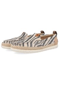 Zapatillas slip-on de lona que presentan un patrón a rayas en blanco y negro, detalles de yute trenzado alrededor de la suela y una parte inferior de goma de color beige claro.