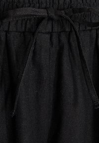 Black linen shorts with an elastic waistband, featuring a matching drawstring. The fabric has a textured, woven appearance.