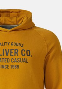 Senfgelbe Kapuzenjacke mit schwarzem Text "QUALITY GOODS OLIVER CO. DEDICATED CASUAL SINCE 1969" und sichtbarer Naht an der Schulter.