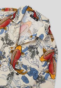 Camisetta a maniche corte caratterizzata da uno sfondo crema con pesci koi rossi e arancioni, nuvole blu e dettagli di bamboo verde. Tessuto leggero.