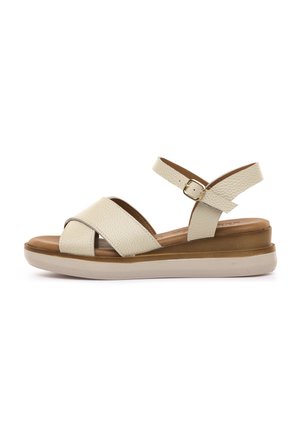 Sandalia de cuero beige con correa ajustable en el tobillo, plantilla acolchada marrón y suela gruesa de goma blanca para uso casual.