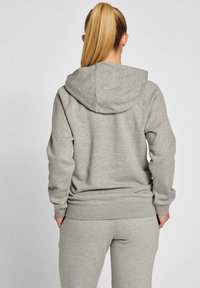 Grå hoodie med avslappnad passform, ficka fram och huva med snörning. Mjuk bomullsblandning. Kombineras med matchande gråa sweatpants.