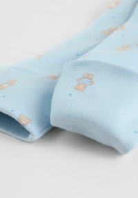 Lyseblå sokker lavet af blødt stof med et mønster af små brune bamser og blå detaljer.