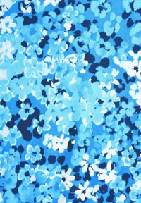 Tyget har ett blommönster i olika nyanser av blått, med ljusblå, mörkblå och vita blommor på en texturerad bakgrund.