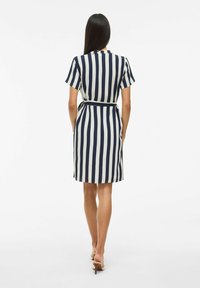 Abito a righe nei colori blu navy e crema, maniche corte, vita con cintura, lunghezza al ginocchio, tessuto morbido e orlo dritto nella parte inferiore.