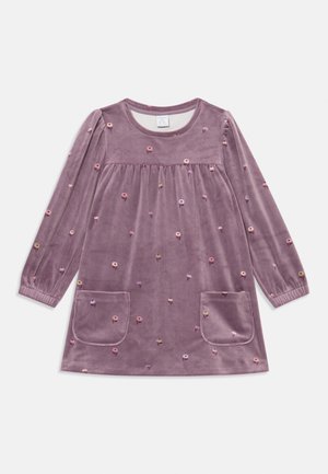 Lilla fløyelskjole med lange ermer, broderte blomsterdetaljer, rund halslinning og to frontlommer. Myk tekstur og avslappet passform.