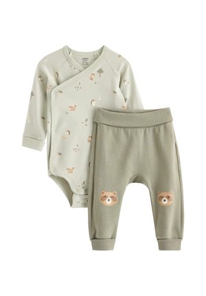Hellgrüner Baby-Wickelstrampler mit Waldtier-Prints und passenden Hosen mit Waschbär-Gesichtern auf den Knien, flach auf weißem Hintergrund ausgelegt.