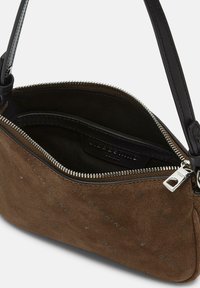 Brązowa zamszowa torba na ramię z częściowo otwartym srebrnym zamkiem, czarną podszewką i regulowanym czarnym paskiem.