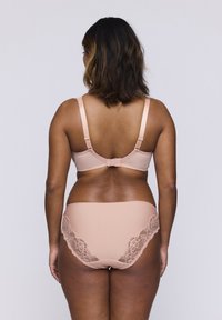 Zestaw biustonosza i majtek w miękkim, nagim materiale. Biustonosz ma regulowane ramiączka i zapięcie na hak; majtki zdobione są koronkowymi akcentami na biodrach.
