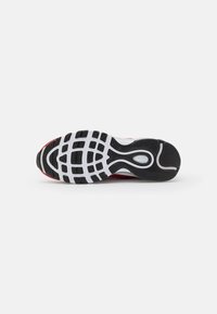 Semelle de chaussure de sport rouge et blanche avec motif d'adhérence noir sur fond blanc.