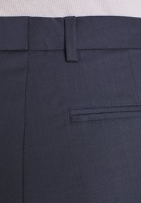 Pantalons bleu marine foncé avec une texture lisse, un design à devant plat et une poche arrière unique avec des coutures discrètes.