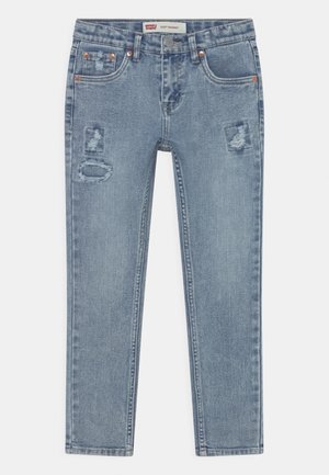 Jeans ajustados de mezclilla azul claro con parches desgastados y un ligero desvanecimiento. Pasadores de cinturón estándar y acentos en tono cobre.