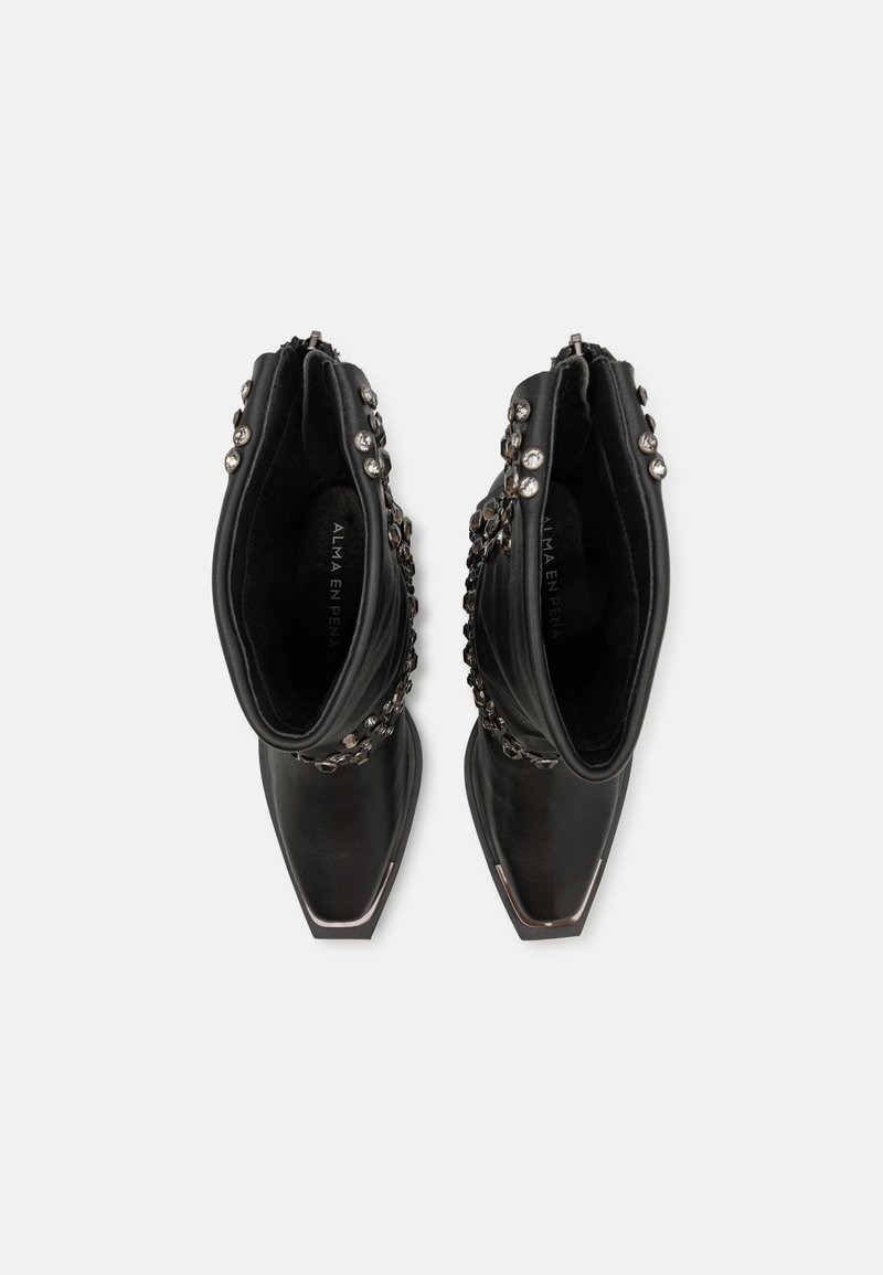 Botines negros de cuero, con puntera afilada, adornados con tachuelas metálicas y una superficie texturizada.
