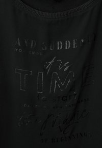 Svart tyg T-shirt med präglad text i olika typsnitt, inklusive fraser som "DAGS att börja" och "magin av början".